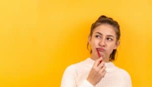 girl brushing her teeth behind a yellow background