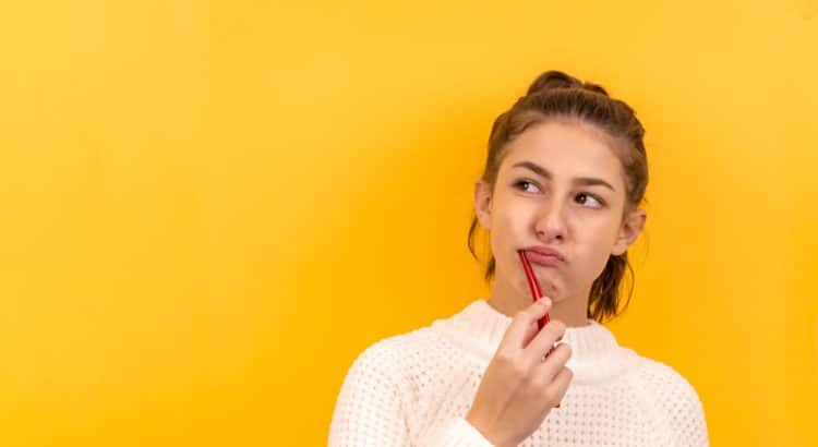 girl brushing her teeth behind a yellow background