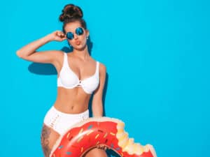 woman in white bikini in front of blue background