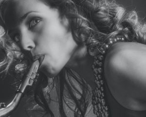 black and white photo of blonde woman blowing on a saxophone