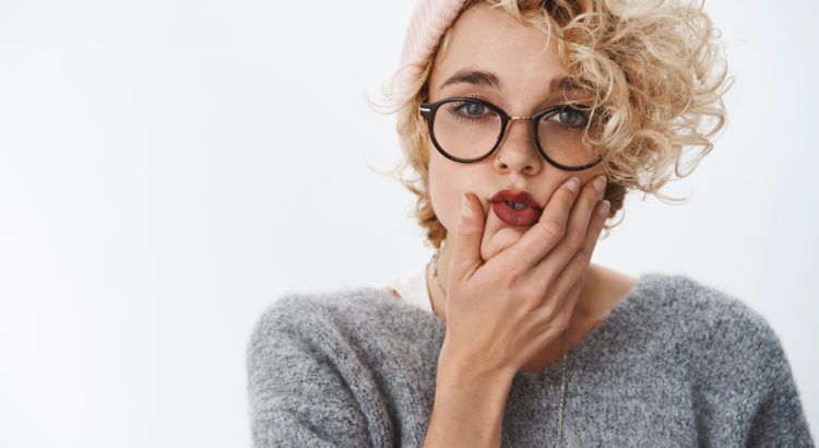 blond girl with red lipstick pink hat and curly hair making a face