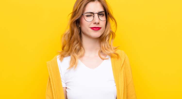 blonde model with red lipstick and glasses in front of yellow background